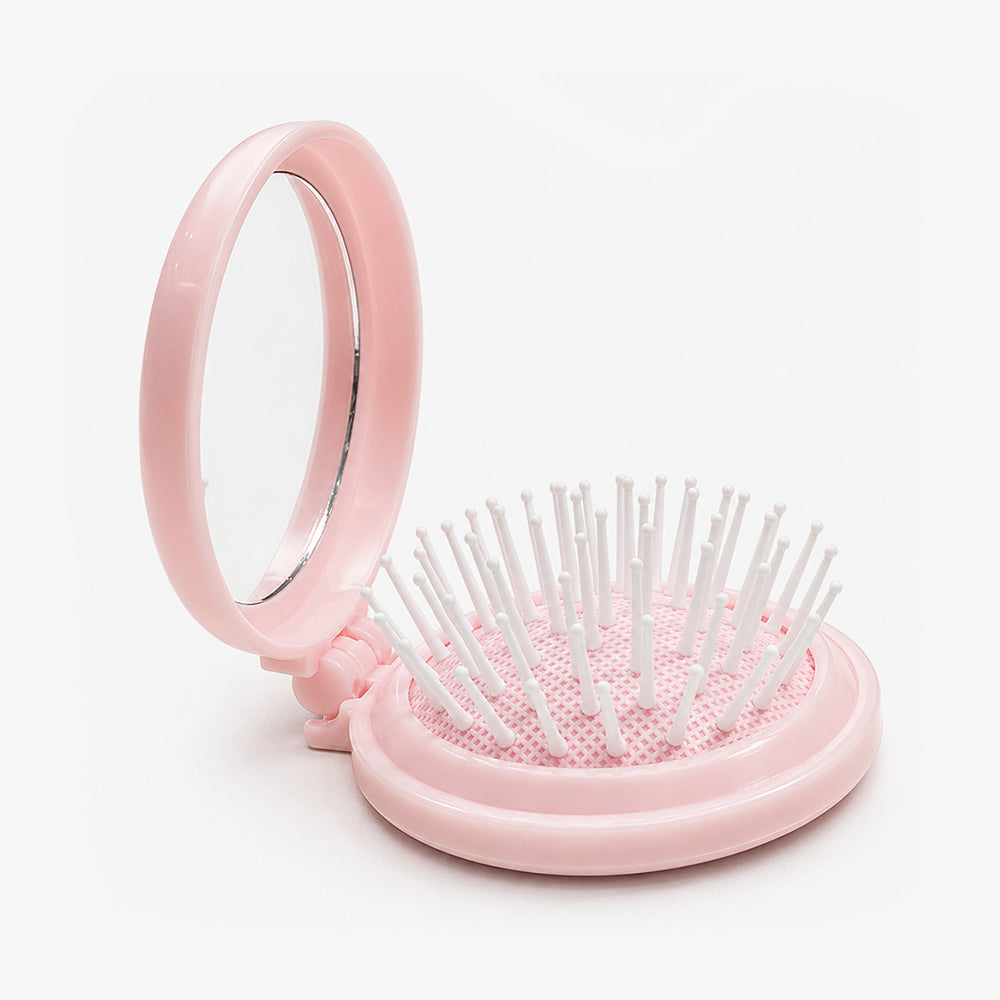 Pink folding hair brush with built-in mirror, white bristles, and textured base