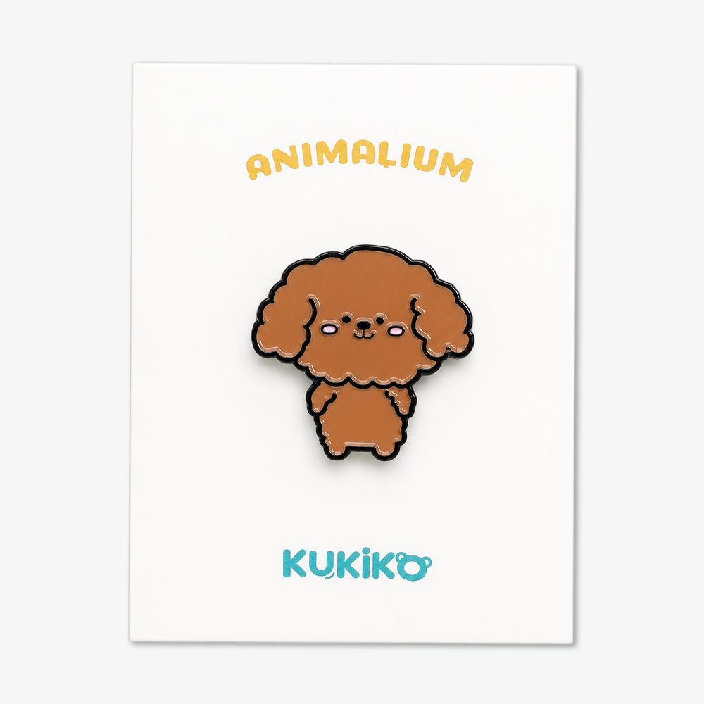 Enamel pin of a brown poodle with black outline and glossy finish on white backing card