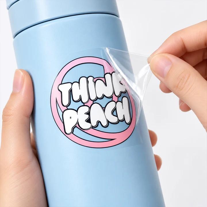 Clear transfer decal with pink circular border and bold white lettering being peeled from backing