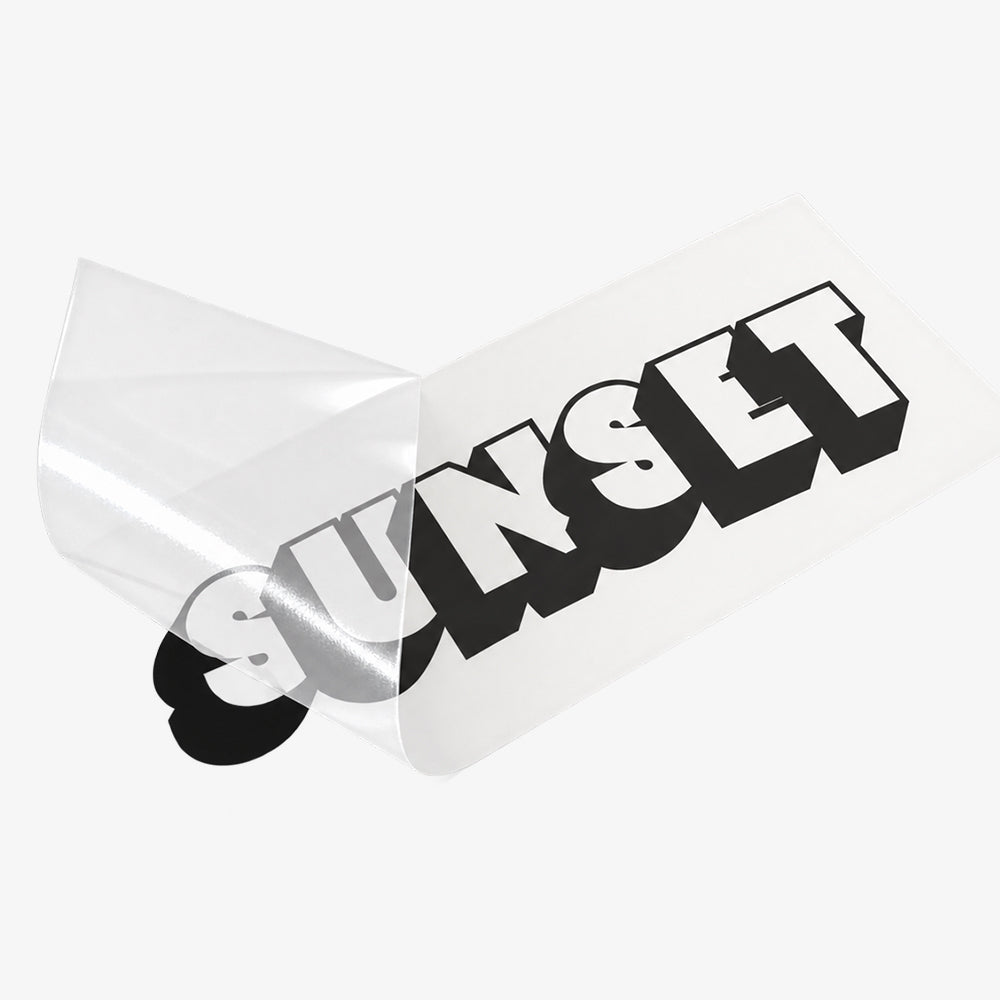 Clear transfer decal with bold black-and-white block letters and a peeled corner revealing adhesive backing