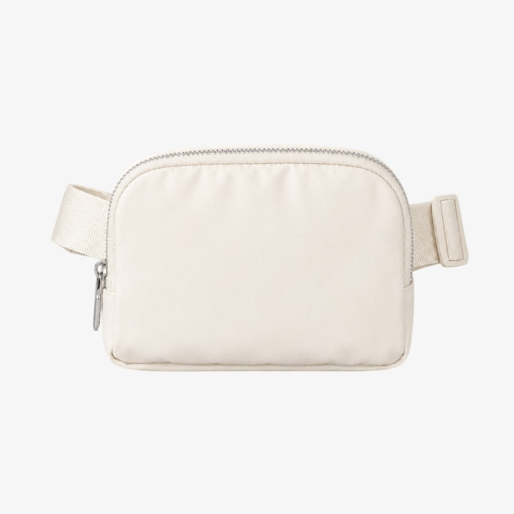 Cream-colored crossbody fanny pack with silver zipper, adjustable strap, and rectangular padded body