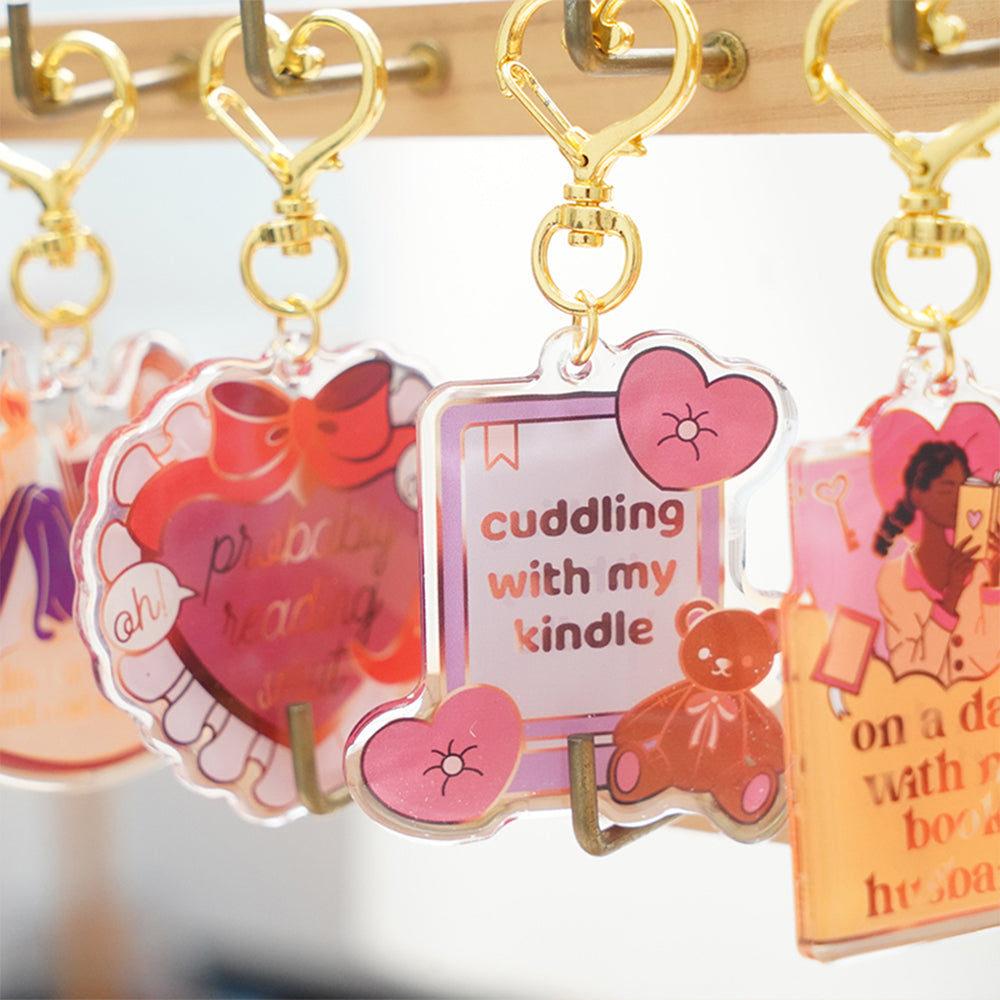 Custom Acrylic Keychains with cute cartoon prints and gold heart-shaped clasps, hanging neatly on a wooden display rack