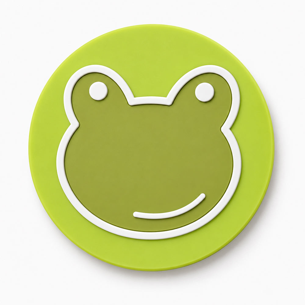 Round green PVC coaster featuring a raised frog face with white outline and eyes