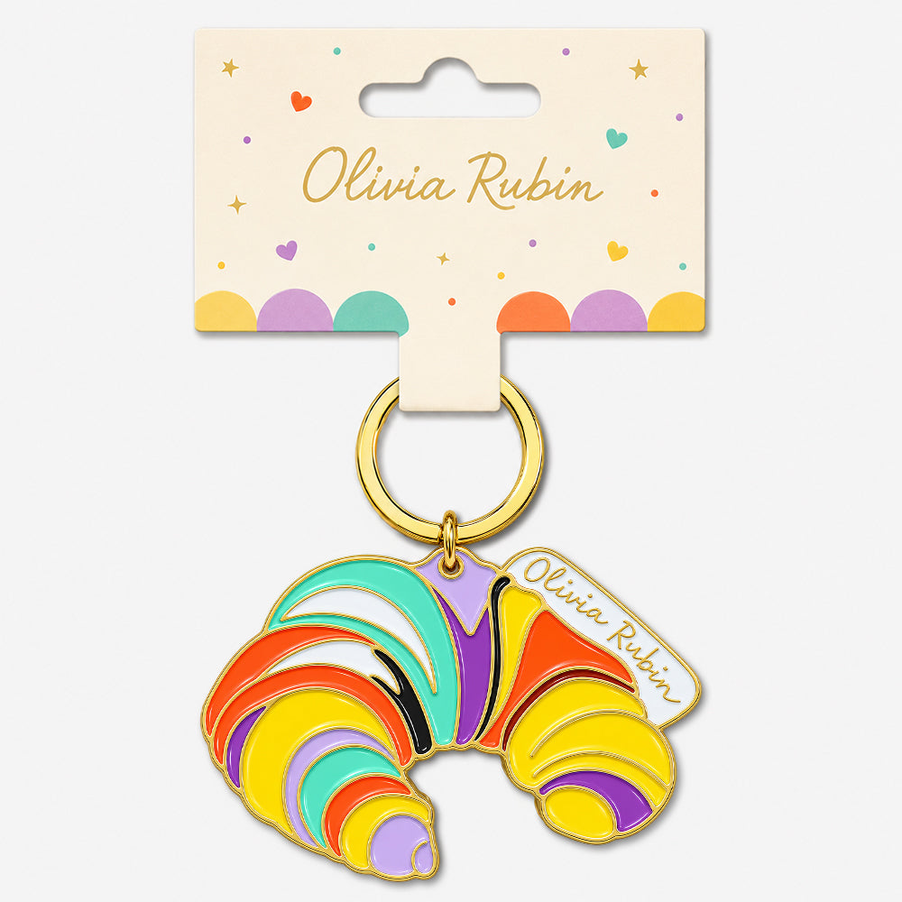 Folded card keychain with rainbow enamel swirls, gold ring, and attached name tag