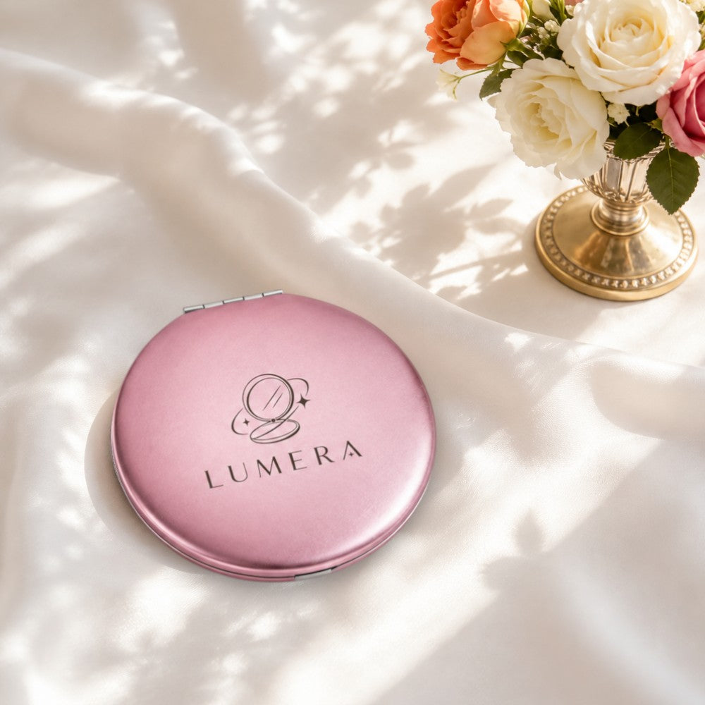 Compact round aluminum mirror in soft pink with a hinged lid and subtle engraved design