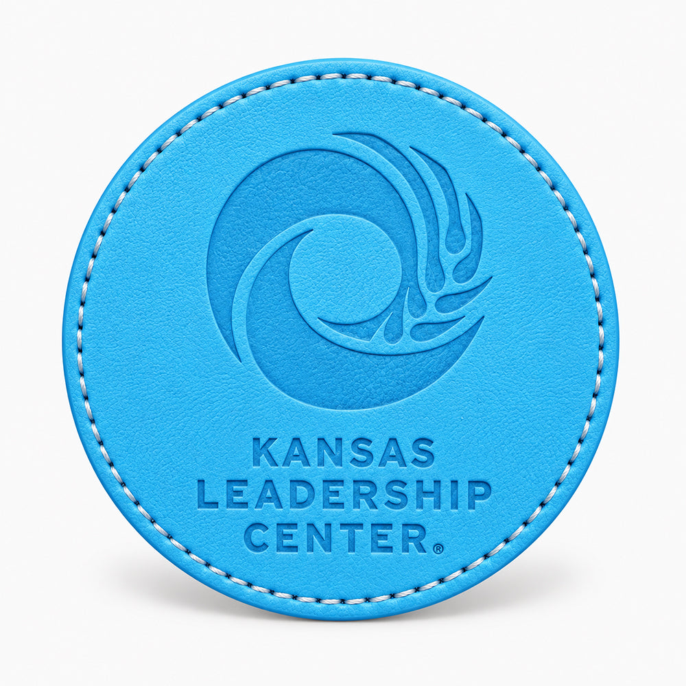 Circular blue leather coaster with white stitching and an embossed swirl design