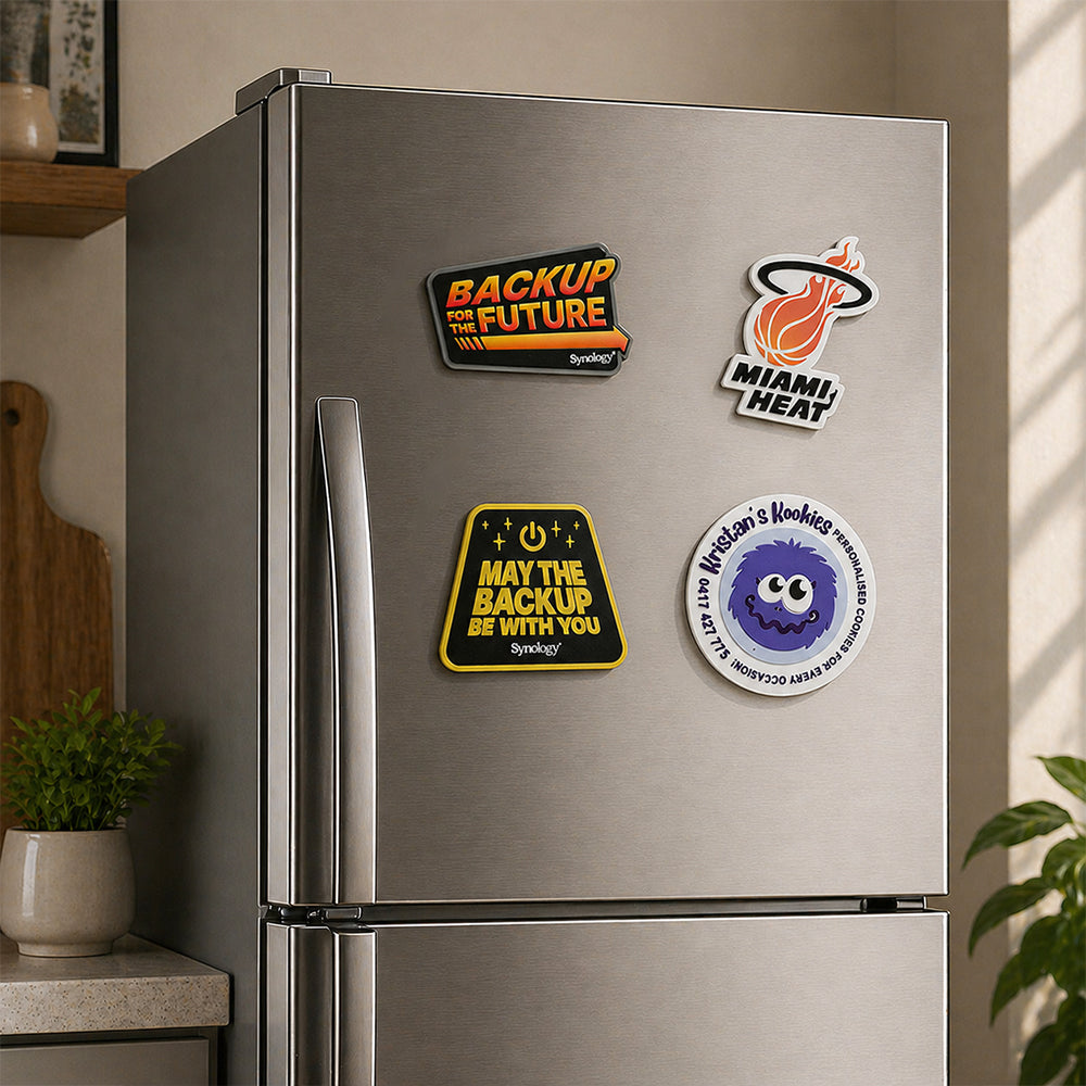 PVC fridge magnets with various fun custom printed designs attached to a stainless steel refrigerator door