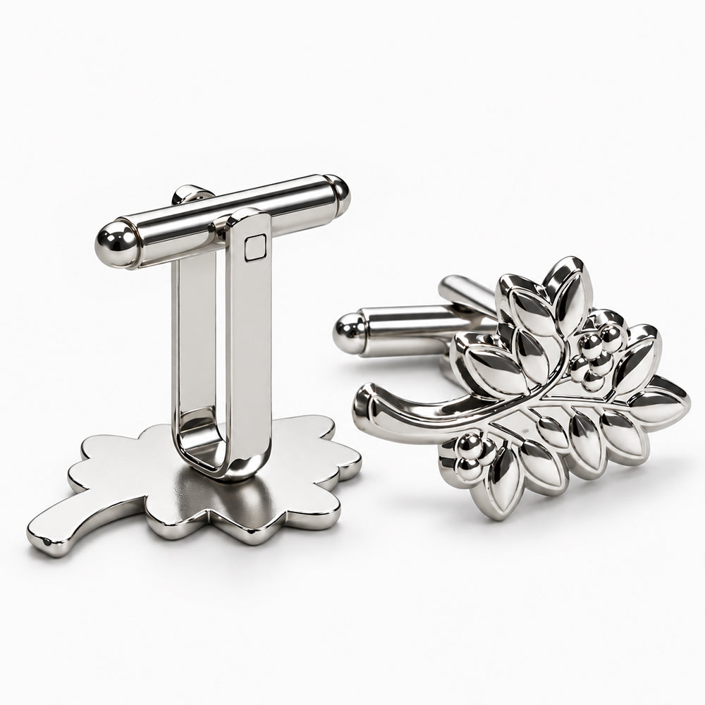 Shiny silver cufflinks with one featuring a leafy branch design and the other a scalloped base