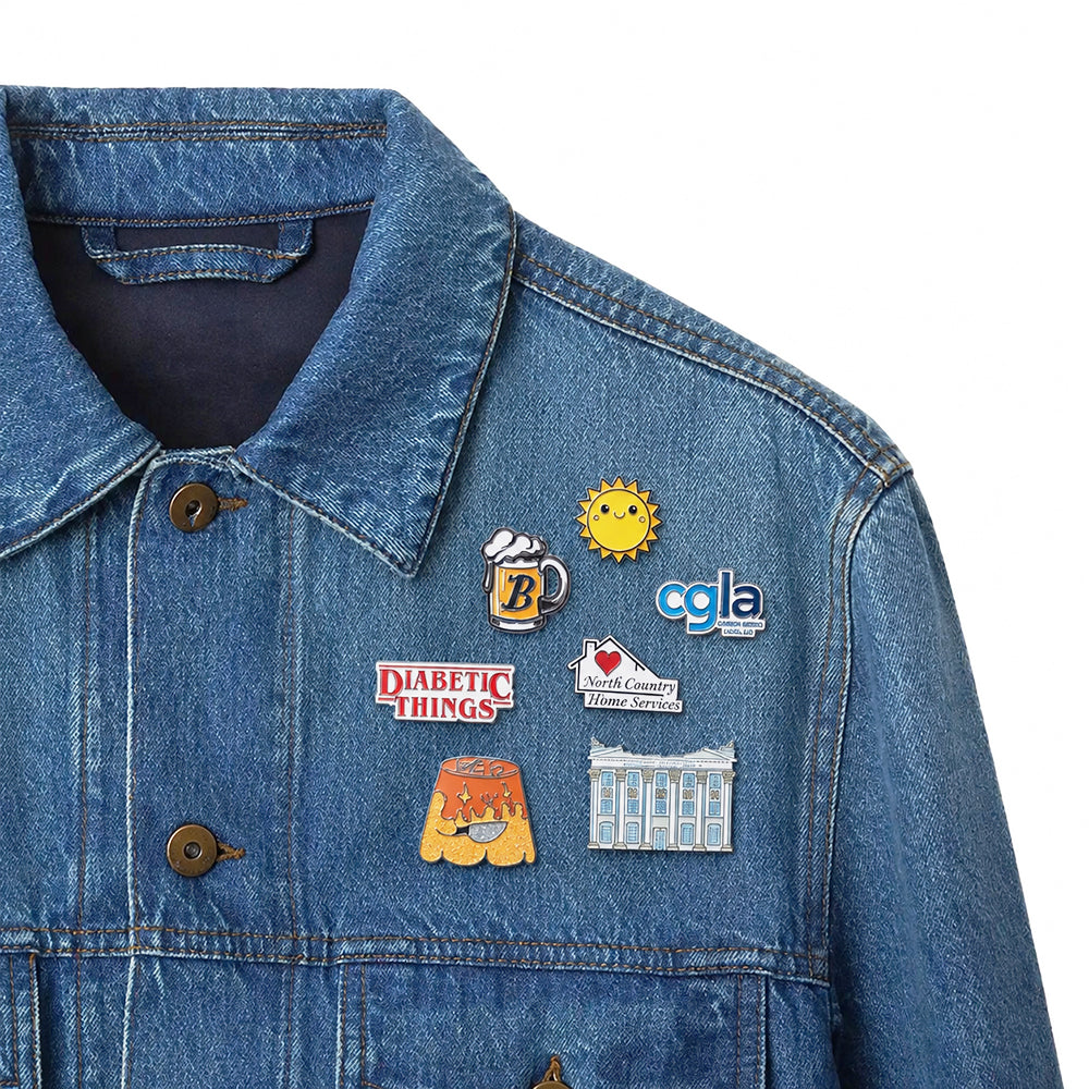 Soft enamel pins with assorted fun custom graphic designs pinned on blue denim jacket lapel as stylish decorative badges
