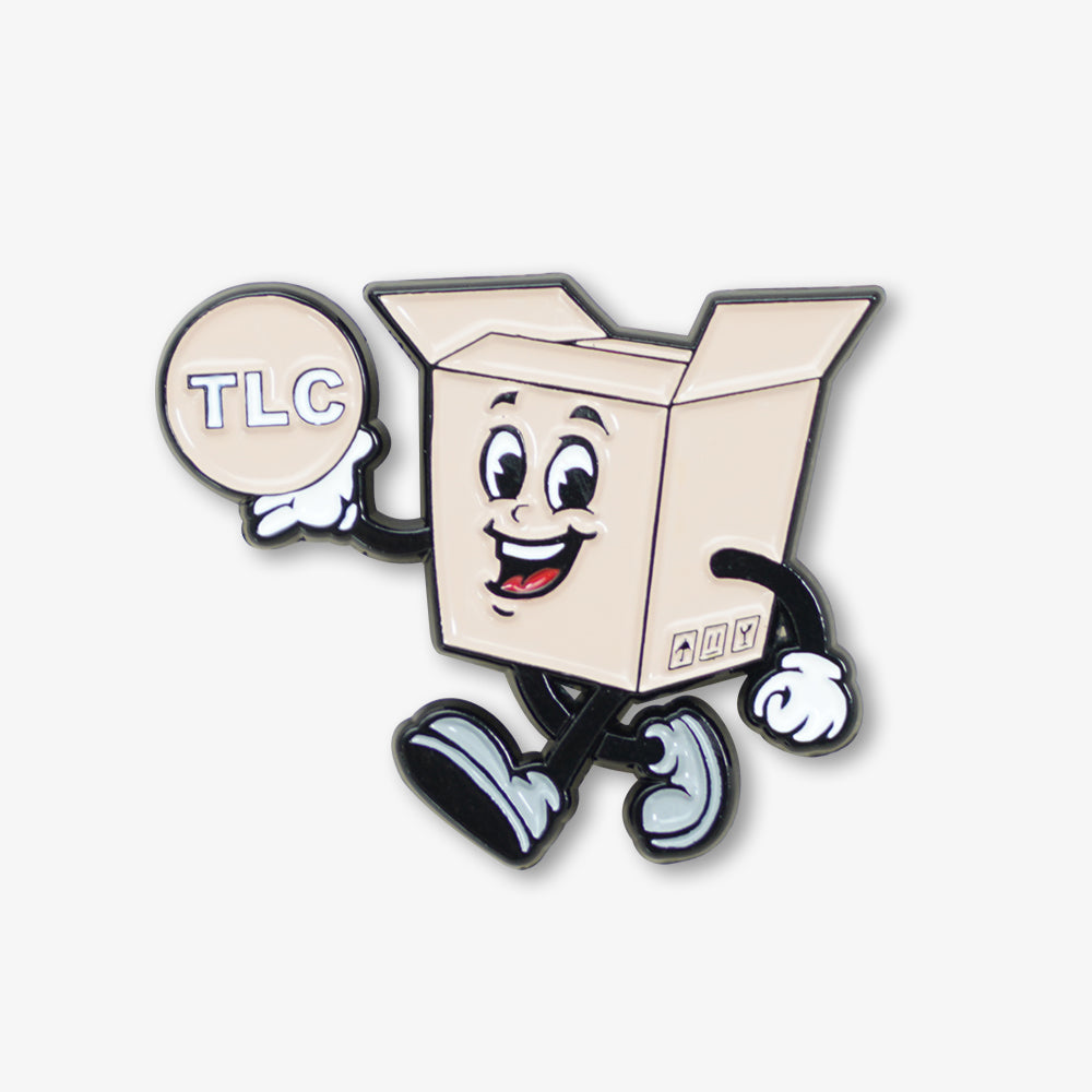 Soft enamel pin featuring a playful retro cartoon cardboard box mascot holding a TLC circular badge
