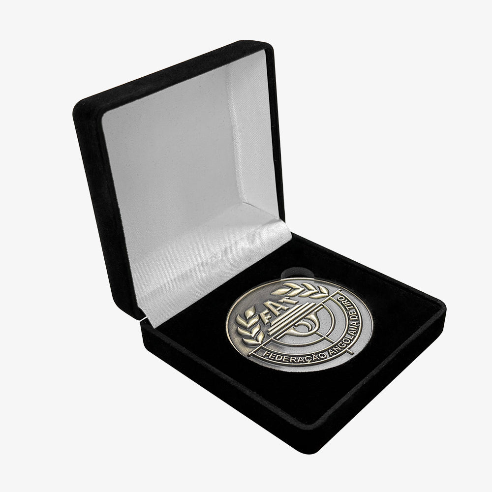Velvet coin box with black exterior and white satin lining, open holding an engraved commemorative metal coin