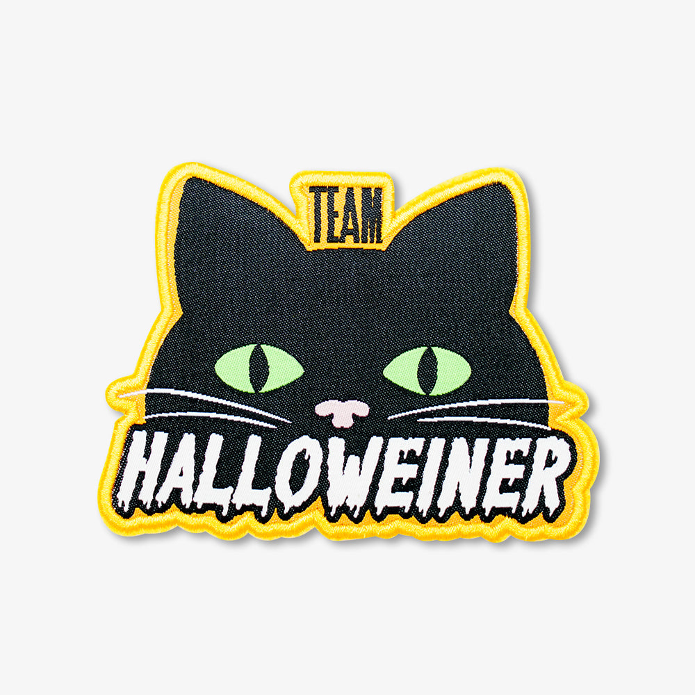 Woven patch shaped as a black cat head with green eyes, yellow stitched border, fun "TEAM HALLOWEINER" Halloween themed design
